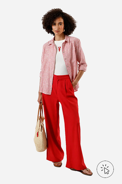 Modelo veste camisa listrada de manga longa vermelha, camiseta off-white com bordado de lagosta, calça de alfaiataria oversized vermelha, bolsa texturizada e rasteirinha marrom.- como usar camisa listrada
