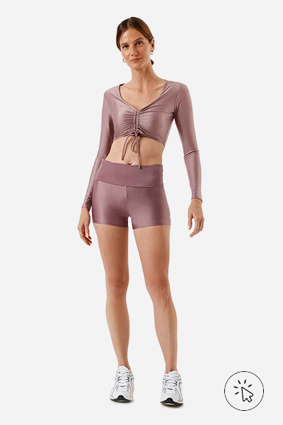 Modelo veste short feminino esportivo ACE cós ajustável rosê e top de manga longa no mesmo tecido e cor