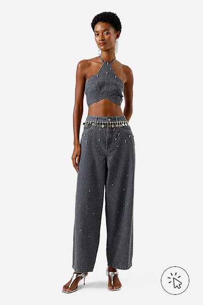 Modelo veste calça baggy feminina jeans com brilhos cinza e top cropped estrela na mesma cor e tecido