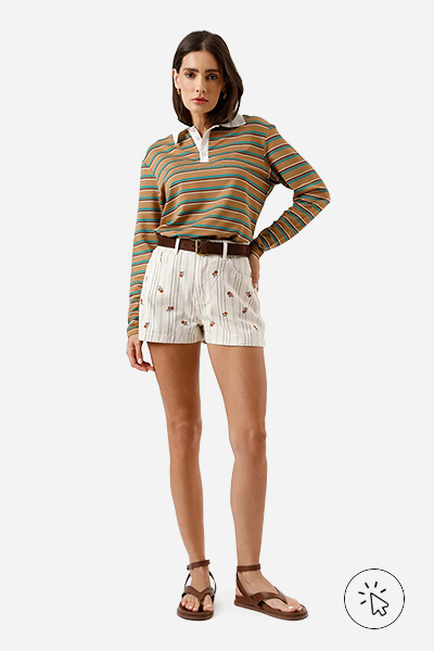 Modelo veste short mom feminino de sarja com bordado floral listrado bege cru e polo manga longa listrada laranja e verde
