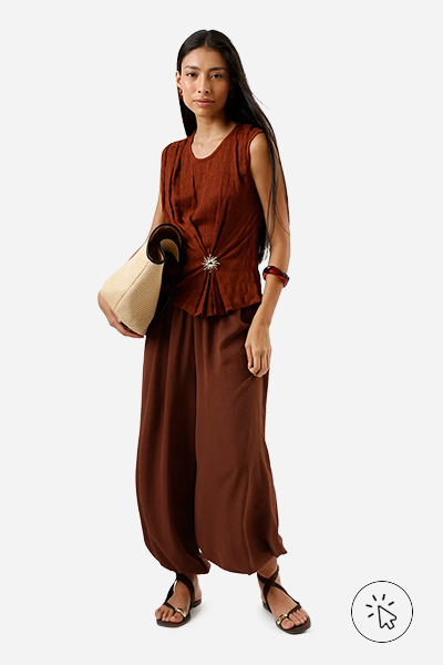 Modelo veste blusa texturizada marrom, calça balloon texturizada marrom, braceletes, rasteirinha marrom e bolsa bege.- tons quentes e frios - tons quentes roupas - paleta tons quentes - quais são os tons quentes e frios