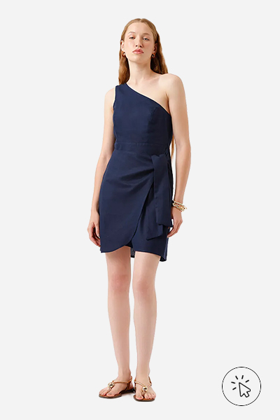 Modelo usa vestido curto de um ombro só em linho azul-marinho, rasteirinha texturizada marrom e braceletes dourados- tons quentes e frios - paleta tons frios - paleta tons frios roupas - quais são os tons quentes e frios 