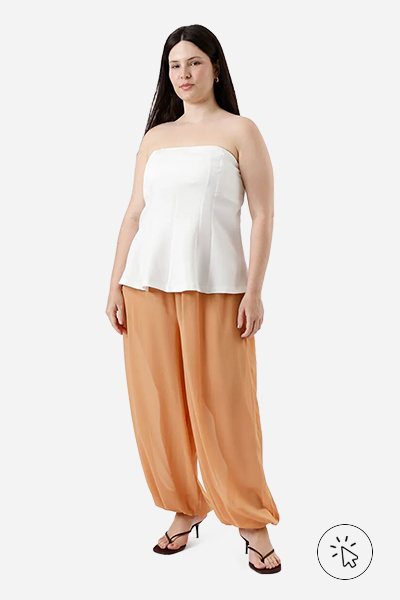 Modelo veste calça aladim laranja, blusa peplum sem alças off-white e tamanco de salto fino marrom - tons quentes e frios - tons quentes roupas - paleta tons quentes - quais são os tons quentes e frios 