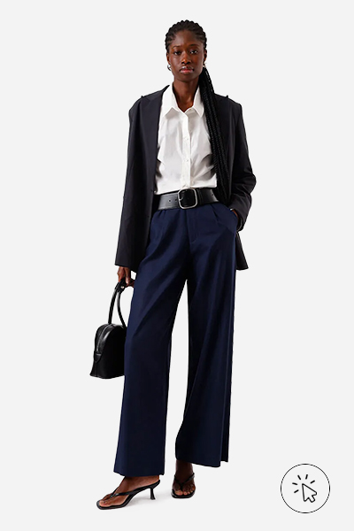 Modelo veste calça de alfaiataria com pregas em linho azul-marinho, camisa oversized off-white, blazer de alfaiataria azul-marinho, cinto, tamanco preto e bolsa preta- tons quentes e frios - paleta tons frios - paleta tons frios roupas - quais são os tons quentes e frios 