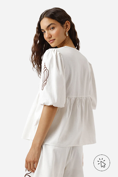 A modelo está usando uma bata off-white. Ela está de costas.  - tecido linho - o que é linho - como lavar roupa de linho - como passar roupa de linho - como é feito o linho 