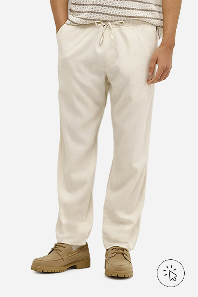A foto é a parte debaixo do look masculino. O modelo está usando uma calça com linho bege.  - tecido linho - o que é linho - como lavar roupa de linho - como passar roupa de linho - como é feito o linho 