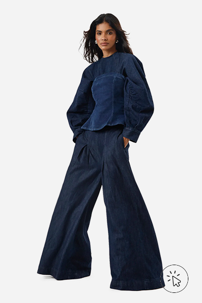 Modelo veste calça ultra wide leg feminina jeans com pregas cintura alta azul