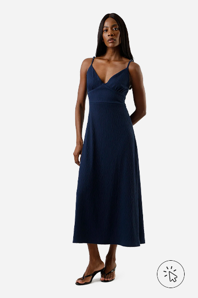 Modelo usa vestido mídi azul-marinho texturizado com alças finas e sandália de salto fino preta - estilo minimalista - estilo minimalista feminino - o que é estilo minimalista