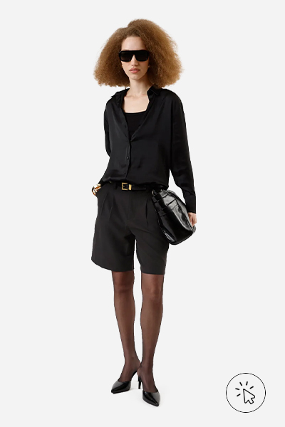 A modelo está usando uma bermuda de alfaiataria, camisa e blusa, tudo preto - look monocromático - o que é monocromático - o que é look monocromático