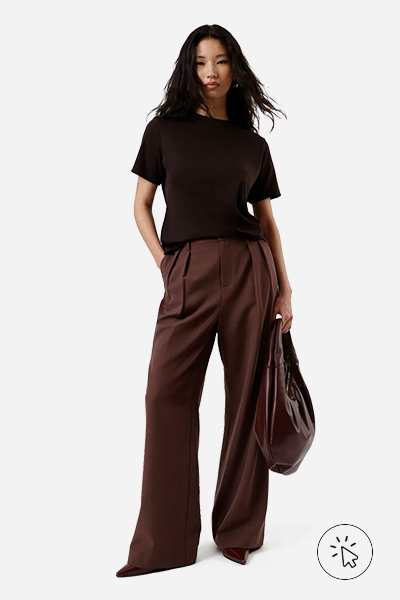 A modelo está usando calça de alfaiataria, camiseta, scarpin e está segurando uma bolsa vinho - look monocromático - o que é monocromático - o que é look monocromático