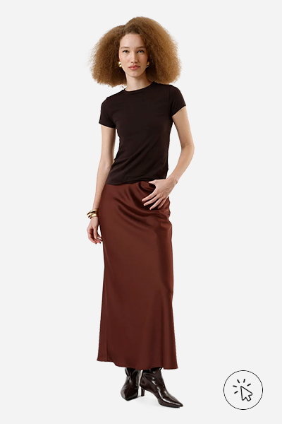 A modelo está usando uma camiseta marrom, saia mídi de cetim e bota de cano alto - look monocromático - o que é monocromático - o que é look monocromático