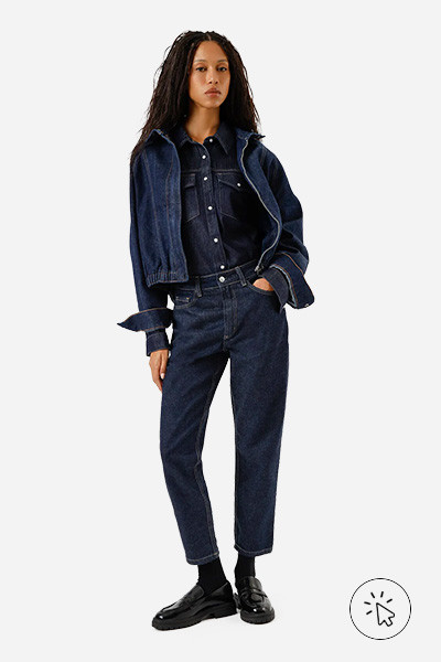 A modelo está usando uma calça, camisa e jaqueta, tudo jeans em lavagem escura - look monocromático - o que é monocromático - o que é look monocromático