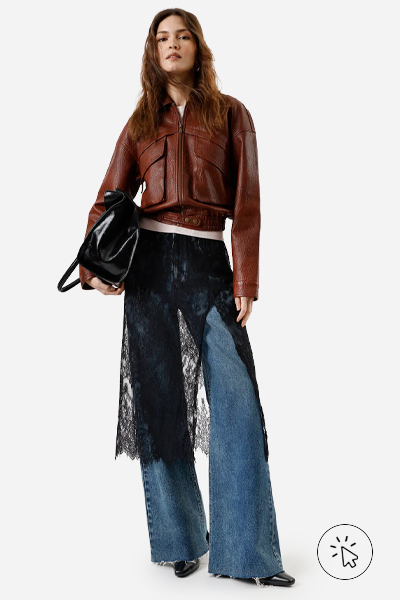 Modelo veste calça wide leg feminina jeans azul com saia mídi de renda preta sobreposta e jaqueta de PU vinho  - moda anos 2000 - o que era moda nos anos 2000 - estilo y2k - o que é y2k