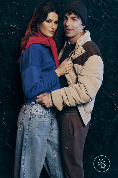 Isabeli Fontana veste suéter azul royal com suéter vermelho amarrado nos ombros e calça baggy jeans. Di Ferrero veste jaqueta puffer bege e marrom e calça de moletom marrom