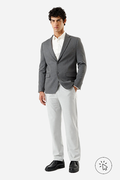 Modelo veste blazer acinturado cinza, camisa off-white, calça reta de alfaiataria cinza e sapato social preto - look masculino para casamento