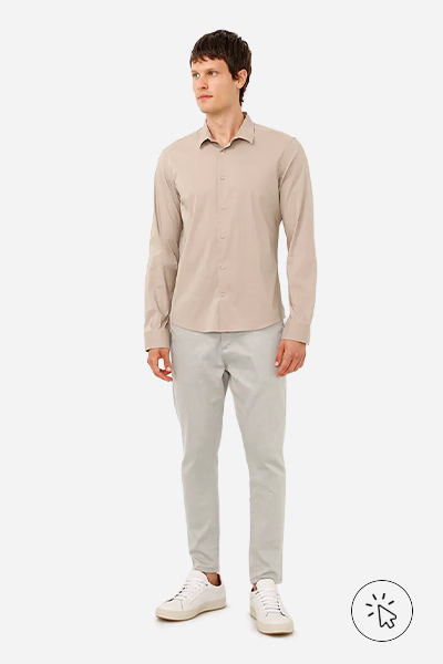 Modelo veste camisa slim fit bege, calça chino de alfaiataria cinza e tênis casual branco - look masculino para casamento