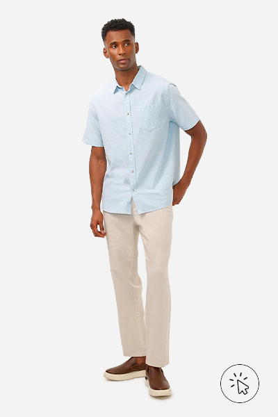 Modelo veste camisa de manga curta de linho azul, calça reta de linho bege e tênis slip on marrom - look masculino para casamento