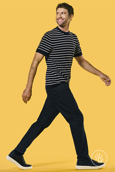O modelo está usando camiseta listrada preta e branca e calça preta