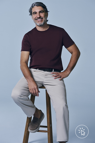 O modelo está usando camiseta vinho e calça clara