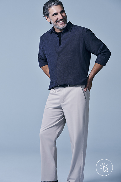 O modelo está usando polo azul-marinho e calça clara