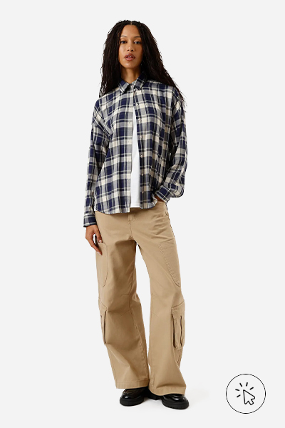 A modelo está usando uma calça baggy bege, uma camiseta off-white e uma camisa de xadrez azul-escuro como sobreposição - estilo grunge - o que é o estilo grunge
