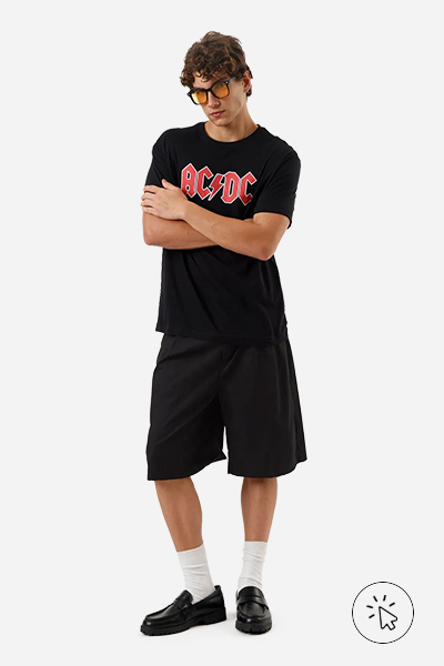 O modelo está usando uma camiseta do ACDS, uma bermuda preta ampla, mocassim e uma meia comprida - estilo grunge - o que é o estilo grunge